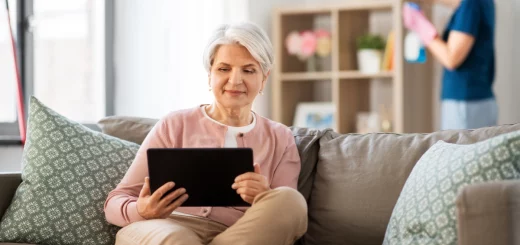 femme âgée heureuse avec une tablette et une aide à domicile qui nettoie sa maison - menageparfait.fr